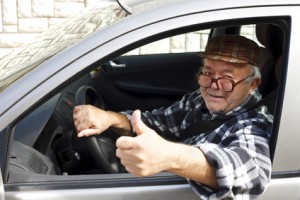 elderly man driving the car and shows the thumb